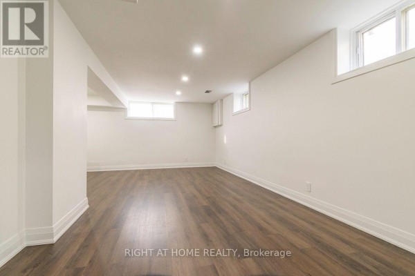 Spacious basement room with white walls and wood plank flooring. - Bsmt - 186 Driscoll Road, Richmond Hill