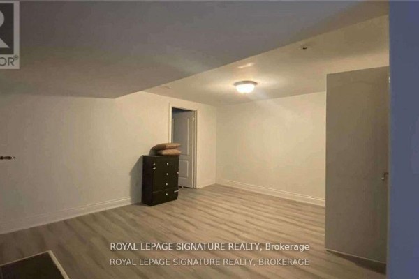 Empty room in the basement with light wood flooring and a closed door. - Bsmt - 2063 Saxon Road, Oakville