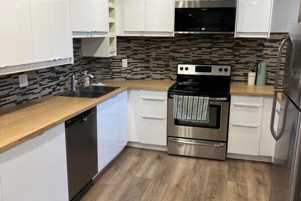Corner view of basement kitchen with wooden countertops, stainless steel sink, and wood-look flooring. - Bsmt - 21 Melbert Road, Toronto