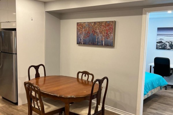 Dining area with wooden table and chairs, artwork on wall, and entrance to bedroom. - Bsmt - 21 Melbert Road, Toronto