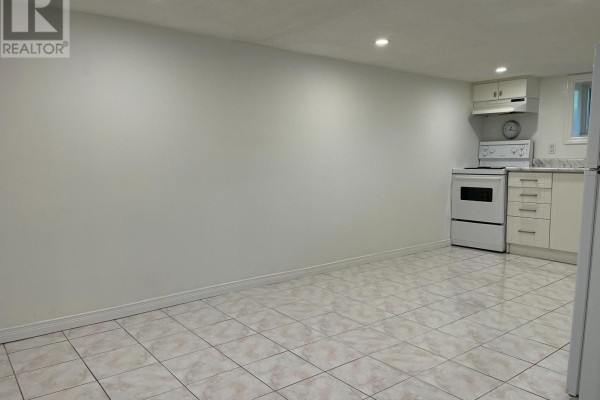 Basement kitchen with white cabinets, a white stove, and tiled floors. - Bsmt - 24 Weymouth Avenue, Toronto