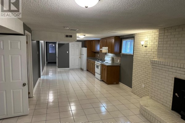 Open-concept basement with kitchenette, white tiled floor, and brick fireplace. - Bsmt - 2546 Palisander Avenue, Mississauga