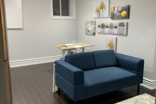 Living space with navy sofa, small dining table with clear chairs, and artwork on wall. - Bsmt - 284 Hickory Circle, Oakville
