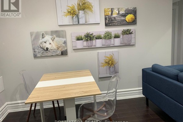 Dining area with a light wood table, two clear chairs, and wall art depicting nature scenes. - Bsmt - 284 Hickory Circle, Oakville