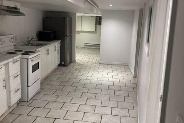 Basement kitchenette with white cabinets, stove, refrigerator, and tiled floor. - Bsmt - 2849 Dufferin Street, Toronto