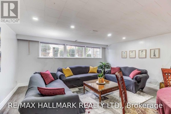 Basement living room with windows, dark grey sectional sofa, and coffee table on a rug. - Bsmt - 30 Amarillo Drive, Toronto