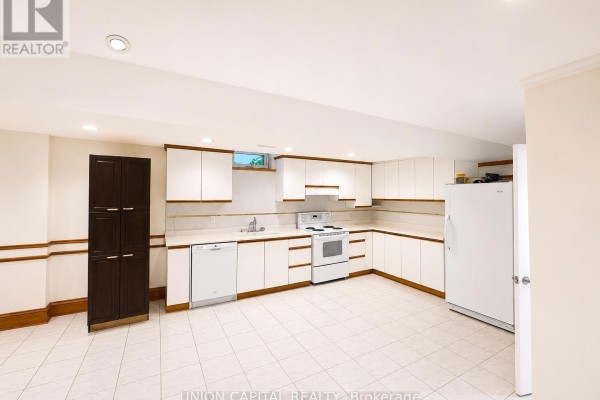 A wide view of the basement kitchen showing white cabinets, appliances, and beige walls. - Bsmt - 300 Belview Avenue, Vaughan