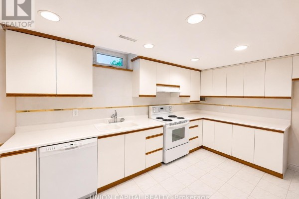 Close-up of the basement kitchen featuring white cabinets, countertop, sink, and a white stove. - Bsmt - 300 Belview Avenue, Vaughan