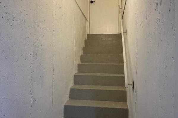 Concrete stairs leading down into a basement with white walls and a metal handrail. - Bsmt - 304 Russet Way, Vaughan