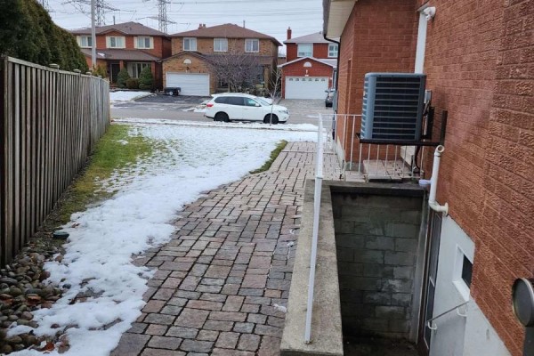 Side view of a brick house with a concrete basement entrance and a paved walkway to the street. - Bsmt - 37 Shawn Place, Vaughan