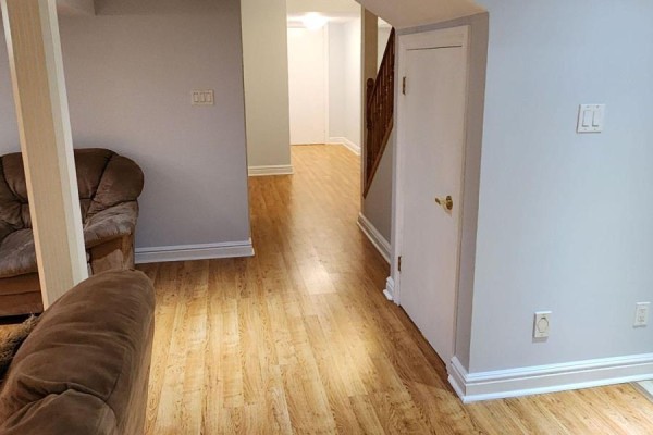 Basement hallway with light wood laminate flooring, neutral walls, and a view towards the stairs. - Bsmt - 37 Shawn Place, Vaughan