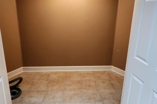 Empty room with light brown walls, beige tiled floor, and white baseboards, showing a vacuum hose. - Bsmt - 37 Shawn Place, Vaughan