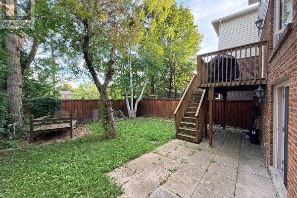 Wooden fence with a birch tree and a gate leading to the driveway. - Bsmt - 39 Aberfeldy Crescent, Markham