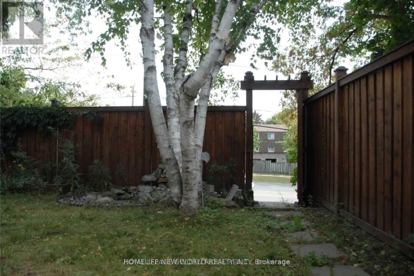 Backyard patio with a brick wall, sliding glass doors, and a parked bicycle. - Bsmt - 39 Aberfeldy Crescent, Markham