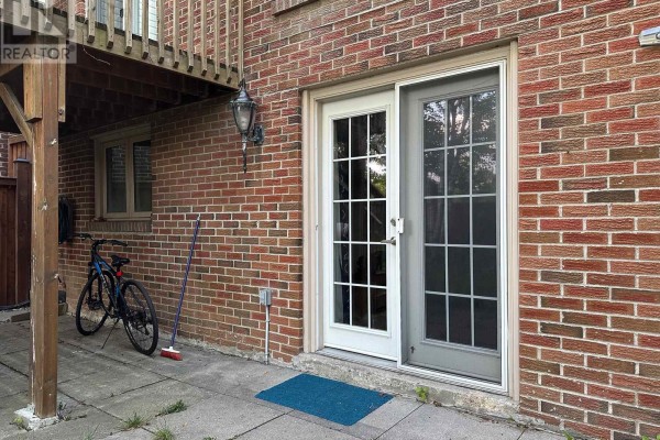 View of a basement recreation room with exercise equipment, fireplace, and doorway to kitchen. - Bsmt - 39 Aberfeldy Crescent, Markham