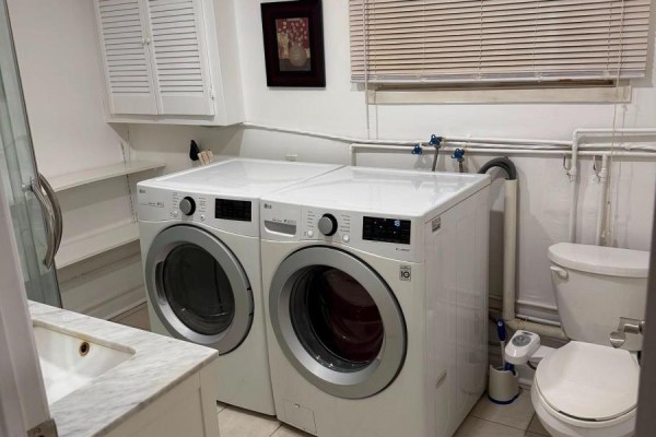 A white LG washer and dryer set are next to a toilet and sink in a room with white cabinets. - Bsmt - 4154 Sunflower Drive, Mississauga