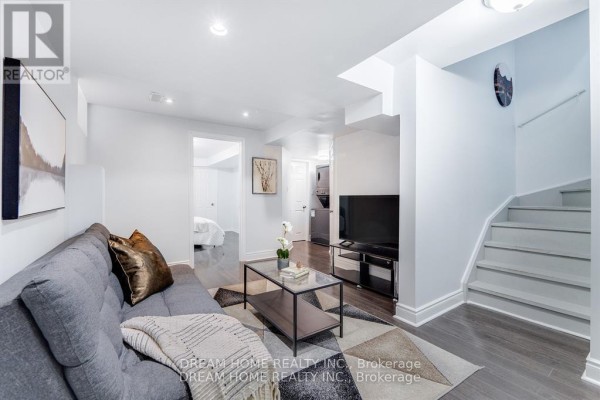 Basement living area with a grey sofa, coffee table, television, and stairs. - #bsmt - 4730 Alana Glen Drive, Mississauga