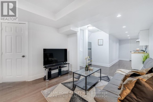 Basement living area with a sofa, coffee table, television, and a small kitchen area. - #bsmt - 4730 Alana Glen Drive, Mississauga