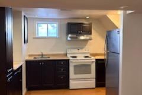 Small unfinished basement room with a white door and wood laminate flooring. - Bsmt - 49 Longford Drive, Newmarket