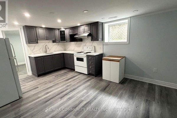 Basement kitchen with dark cabinets, white appliances, and light gray walls. - Bsmt - 51 Sharbot Avenue, Toronto