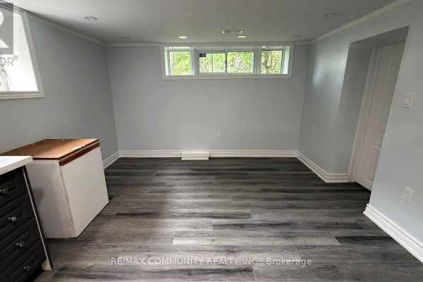 Basement living area with light gray walls, gray wood-look vinyl flooring, and windows. - Bsmt - 51 Sharbot Avenue, Toronto