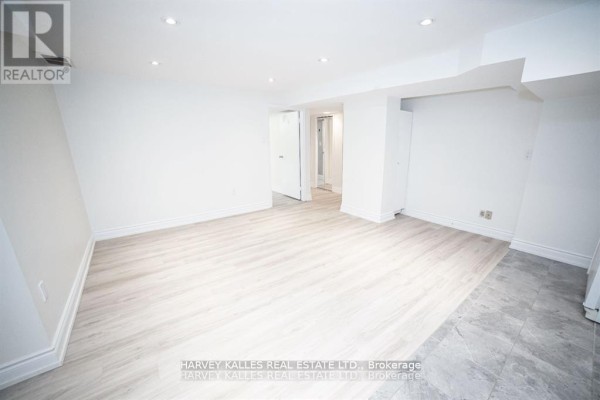 Empty basement living room with white walls and light wood laminate flooring. - Bsmt - 550 Glencairn Avenue, Toronto