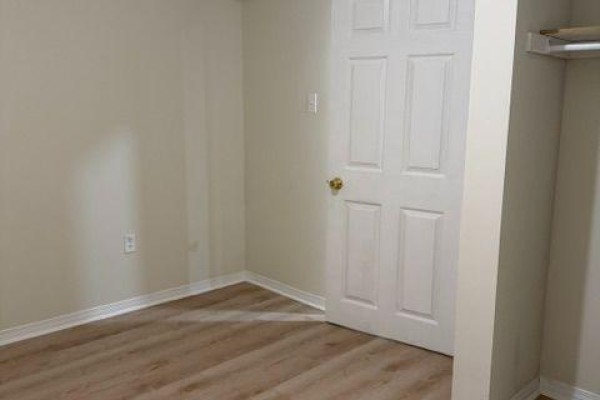 Room with light beige walls, light wood-look vinyl flooring, and a white door. - Bsmt - 584 Doubletree Lane, Newmarket