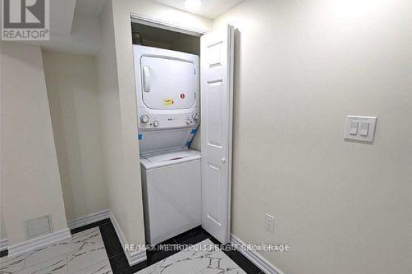 Stackable white washer and dryer in a closet with bifold doors. - Bsmt - 595 Gibbons Street, Oshawa