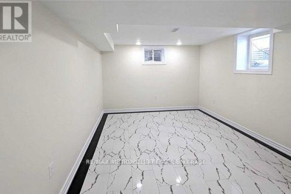 Empty basement room with white walls and large marble-patterned floor tiles. - Bsmt - 595 Gibbons Street, Oshawa