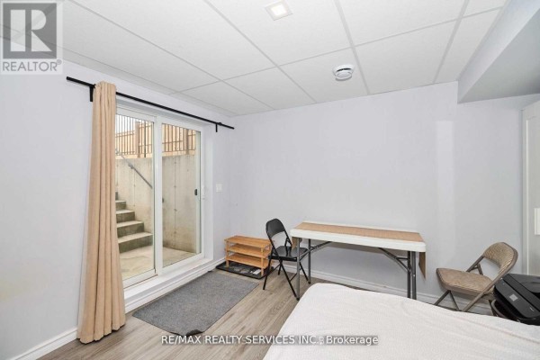 Room with sliding glass doors leading to exterior stairs and a wooden shoe rack. - Bsmt - 6045 Ernest Crescent, Niagara Falls