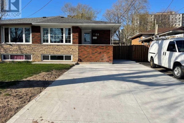 View of a brick house with a concrete driveway and a white van parked on the right. - #bsmt - 64 Gainsborough Road, Hamilton