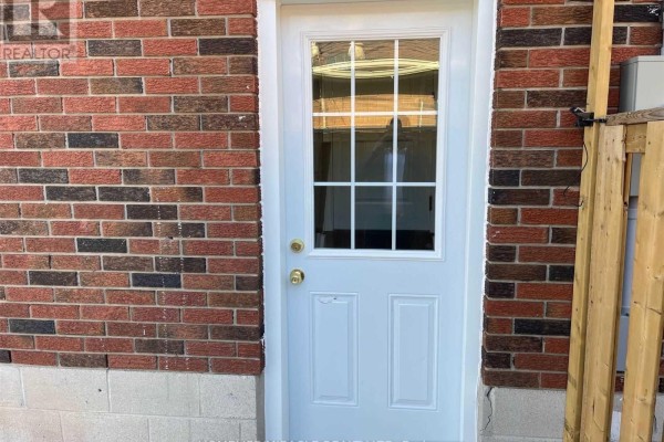 White door with a glass pane and grid pattern, set against a red brick wall. - #bsmt - 64 Gainsborough Road, Hamilton