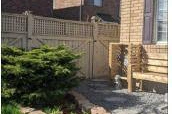 Wooden fence and gate with a green bush in the foreground. - Bsmt - 657 Thompson Road S, Milton
