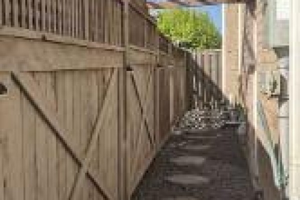 Narrow pathway between a wooden fence and the house, with stepping stones. - Bsmt - 657 Thompson Road S, Milton