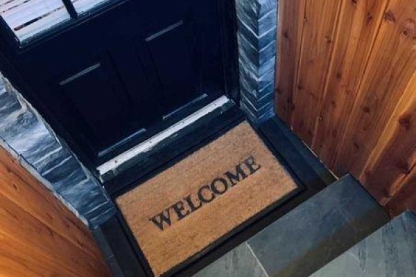 Close-up of a black front door with a 'WELCOME' mat on a stone doorstep. - Bsmt - 66 Richmond Street, Richmond Hill