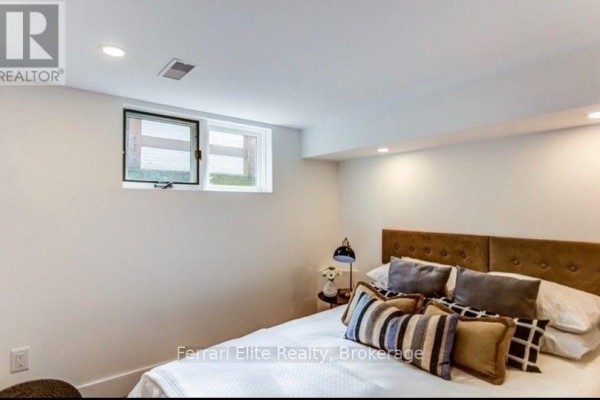 Basement bedroom with a king-sized bed, tufted headboard, and a small window with a view of the outdoors. - Bsmt - 66 Richmond Street, Richmond Hill