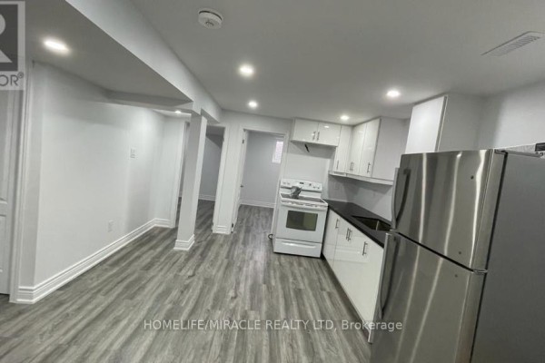 View of the basement kitchen and dining area with light grey laminate flooring. - Bsmt - 7010 Cordingley Crescent, Mississauga
