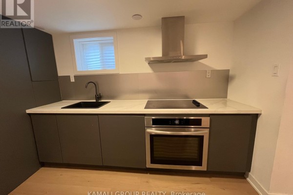 Close-up of modern basement kitchen with dark grey cabinets, black sink, and stainless steel oven. - Bsmt - 75 Newbury Drive, Newmarket