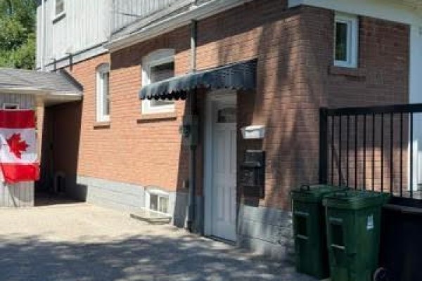 Close-up of the brick exterior, showing the side entrance with a black awning and Canadian flag. - Bsmt - 78 Cree Avenue, Toronto