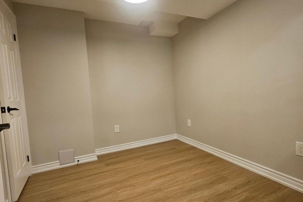 Empty basement room with beige walls, white trim, and light wood laminate flooring. - Bsmt - 79 Mantz Crescent, Whitby