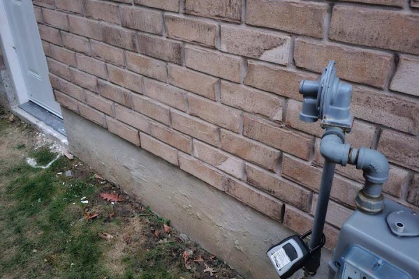 Close-up of the brick exterior wall, showing a gas meter and utility pipe. - Bsmt - 95 Northglen Boulevard, Clarington