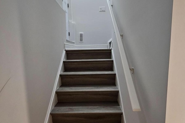 Interior view of a carpeted staircase with wood-look treads leading upwards. - Bsmt - 95 Northglen Boulevard, Clarington