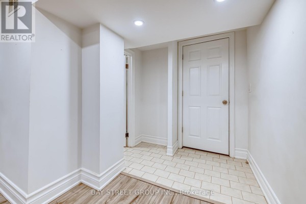 Basement hallway with white walls, beige tiled floor, and white paneled doors. - Bsmt - 99 Cherrywood Drive, Newmarket