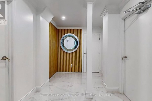 Hallway with white walls, white trim, and a wood-slatted accent wall with a circular mirror. - Bsmt 2 - 26 Lyle Way, Brampton