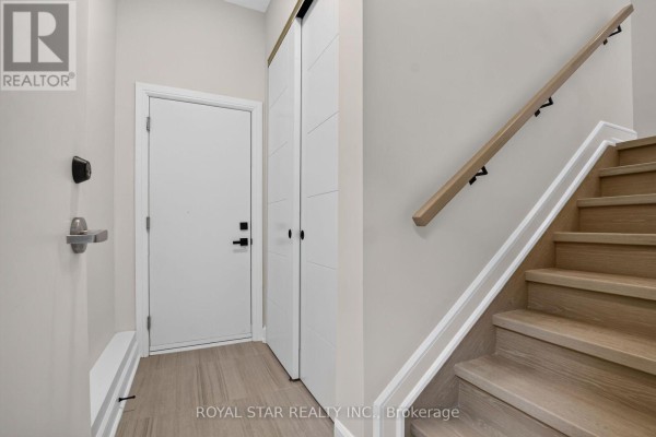 Interior foyer with a white door, double closet doors, and a light wood staircase with black railings. - Bsmt #b - 522 Mutual Street, Ottawa