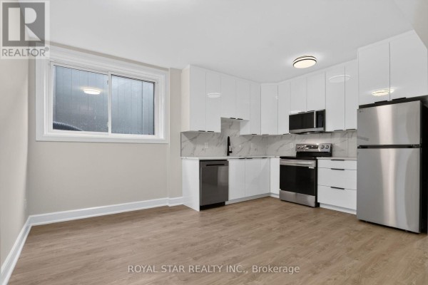 A modern white kitchen with stainless steel appliances, marble backsplash, and light wood flooring. - Bsmt #b - 522 Mutual Street, Ottawa
