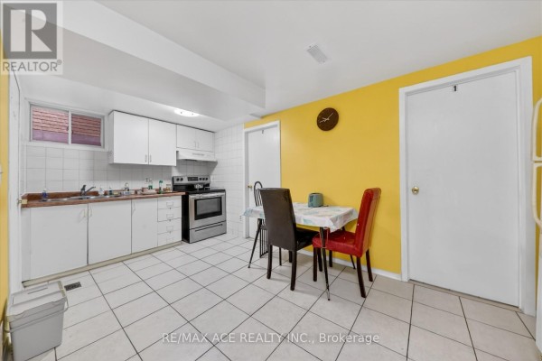 Basement kitchen with white cabinets, a stove, oven, microwave, and a small dining table. - Bsmt Room 1 - 83 Ward Avenue, Hamilton