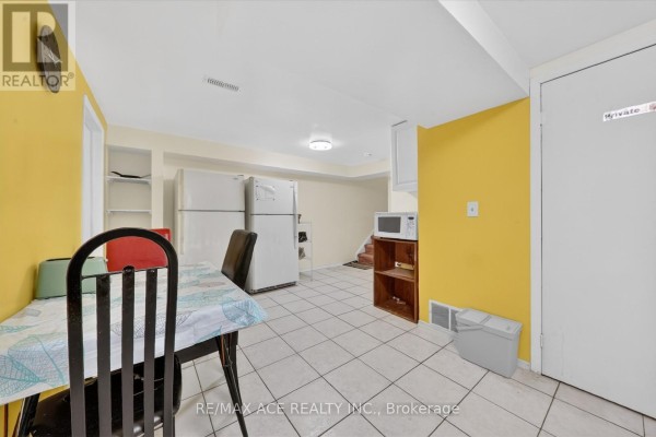 Basement kitchen area with white cabinets, two refrigerators, a microwave, and a dining table. - Bsmt Room 1 - 83 Ward Avenue, Hamilton