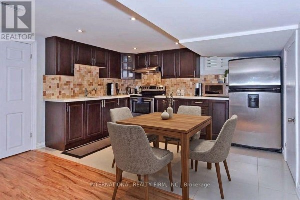 Basement apartment kitchen with dark brown cabinets, stainless steel appliances, and a small dining table. - Bsmtapt - 328 Sheppard Avenue, Pickering