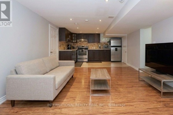 Basement apartment living area with a sofa, coffee table, entertainment unit, and laminate flooring. - Bsmtapt - 328 Sheppard Avenue, Pickering